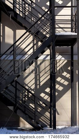 black iron ladder casts a shadow on the pink wall