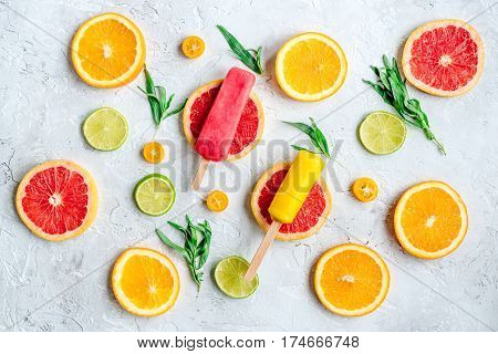 homemade citrus popsicles with fresh fruit slices on stone table background top view pattern