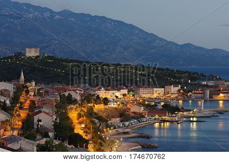 Senj Croatia. A small town in northern Croatia located on the Adriatic coast - night view. The view of the city and harbor from the hill in the northern part of the city. On the hill behind the town is the fortress Nehaj.
