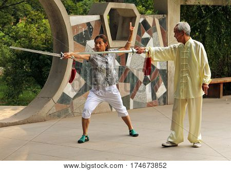 Yinchuan, China - Jul 7, 2011: Chinese Woman Doing Wushu Jian Form Under The Guidance Of A Mentor. T
