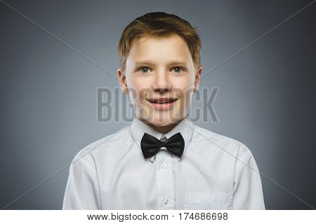 Closeup Portrait of handsome boy with astonished expression while standing against grey background.