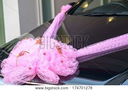 Wedding car in the front of house. Luxurlous car decoration as a wedding car with pink ribbon.