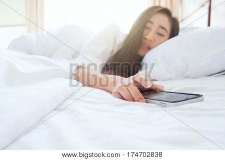 Sleeping Woman Being Woken By Mobile Phone In Bedroom