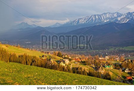 Scenic view of Koscielisko village near Zakopane with panorama of snow caped High Tatras on background Poland in sunlit at spring evening