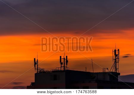 Sunset light shining through the clouds into the sky and the phone antenna.