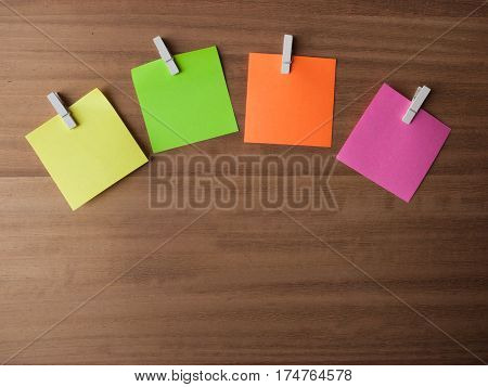 Four Post It notes displayed in an arc on small pegs layed out on softly grained wood