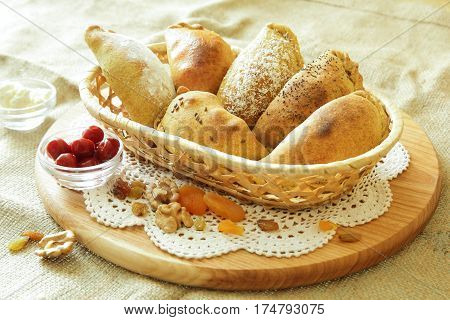 Russian pirozhki, baked patties or pies on basket with nuts and dried apricots