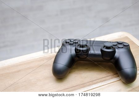 Video game controller on wooden desk with brick  wall background, copy space for text, color tone effect.