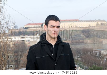 Photographing Danila Mazić with a black coat and black pants a background Petrovaradin fortress and the Danube, Novi Sad, Serbia