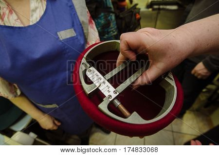 Tailor is controlling  the size of  manufacturing hats  in a factory