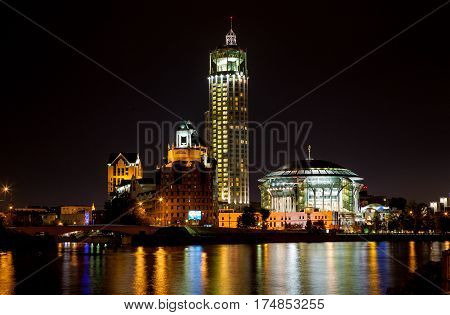Night panorama of the Moscow House of Music is reflected in the Moscow river, Russia.