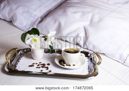 Morning coffee in bed on elegant silver serving tray. Cup of coffee on exquisite embroidered napkin as best hotel service concept.