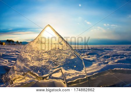 Sun at sunset shining through the transparent texture of the ice.