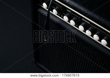 Close up of Black guitar amplifier with jack cable on black background.