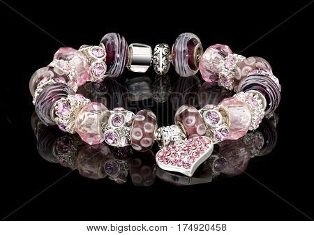 style silver bracelet with white charms isolated on black glass background