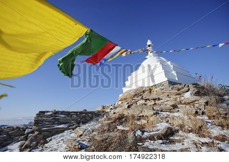 White Buddhist stupa with colorful flags. Ogoi island. Baikal landmark. Russia