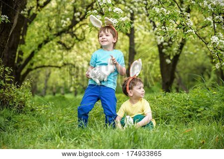 Two Little Kids Boys And Friends In Easter Bunny Ears During Traditional Egg Hunt In Spring Garden,