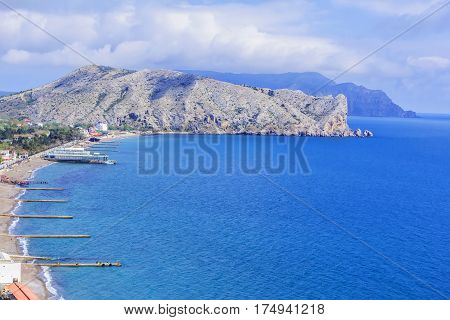 Background blurred landscape view from above to the Sudak Gulf, Cape Alchak and the city of Sudak and its embankment in the Crimea