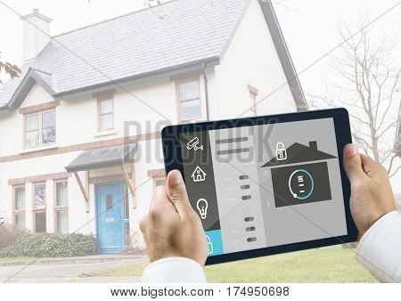 Man holding a digital tablet with home security concept against house in background