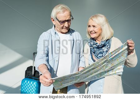 portrait of senior man looking at traveling map with wife near by traveling concept