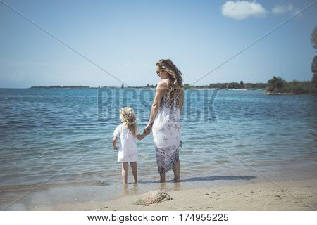mother with child girl by the sea. Sunset portrait. Outdoor. Summer. Woman with girl. Happy family relaxing by sea.