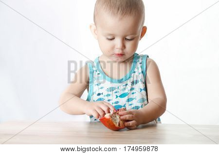 Baby eats a pomegranate ripe and juicy very tasty and joyfully