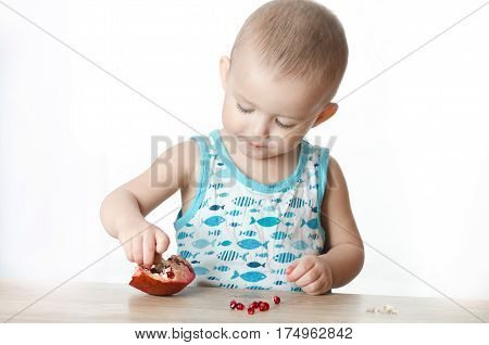 Baby eats a pomegranate ripe and juicy very tasty and joyfully