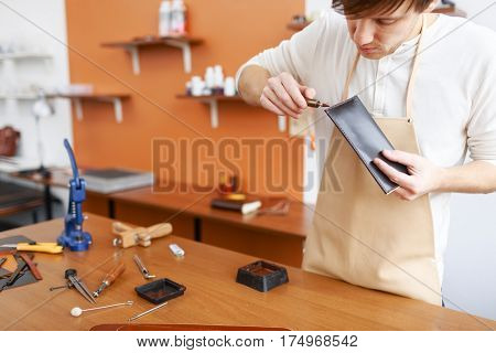 Upholsterer finishing new leather wallet