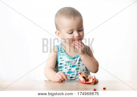 Baby eats a pomegranate ripe and juicy very tasty and joyfully