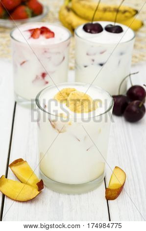 Strawberry, banana and cherry yoghurt on a white wooden background. Healthy diet