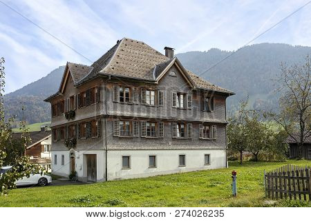 Old Residential House Covered With Wooden Shingle. Town Of Andelsbuch, District Of Bregenz, State Of
