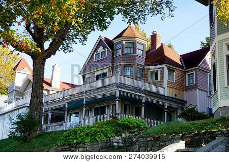 An Elegant Three Story Victorian Summer Cottage, With A Balcony Over Its Wraparound Porch, And A Cor