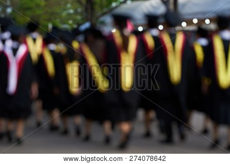 Blurr Image Of A Group Of Graudates On Black Gown Walking On The Street