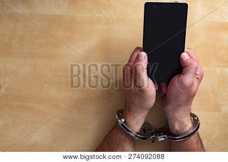 Crime Concept In The Network. Shaking Hands Holding A Mobile Phone.