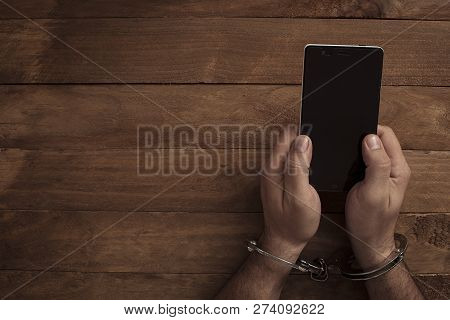 Crime Concept In The Network. Shaking Hands Holding A Mobile Phone.