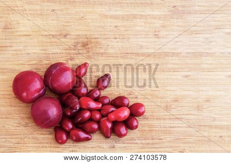 Bright Red Dogwood (cornel)  And Plums Lay On The Light Wooden Background. Close Up, Copy Space.