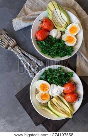 Quinoa Buddha Bowls With Baked Tomatoes, Avocado, Kale, Boiled Eggs And Greek Yogurt On Gray Concret