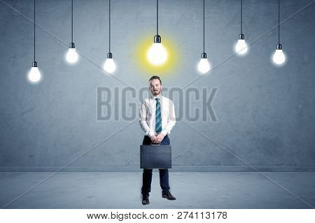 Handsome businessman in an empty space with bulbs above and uninspired face