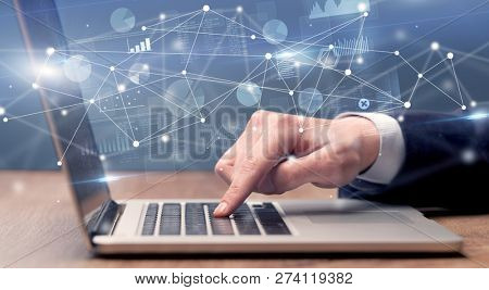 Businessman typing on laptop with linked reports charts grapghs around