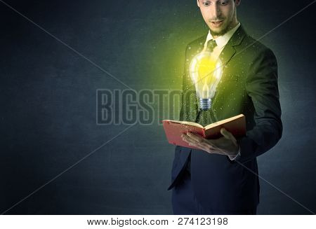 Businessman holding book with bulb.