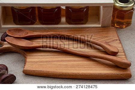 Honey Of Different Varieties In Small Jars, With Wooden Kitchen Utensils.