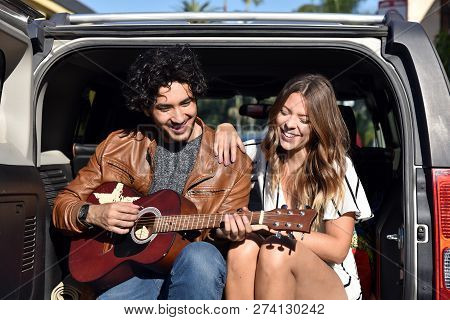Handsome Young Man Seranading A Pretty Young Woman With A Guitar