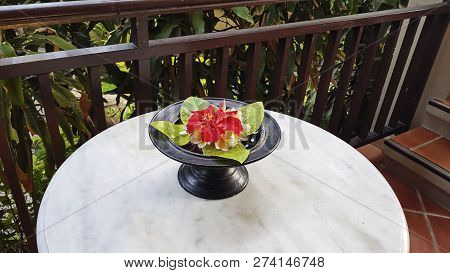 On The Table There Is A Plate With Petals And A Red Flower In The Middle. Indonesian Rite.