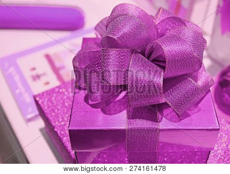 Shiny Purple Pink Square Shaped Gift Box With Gritter Ribbon Bow, Selective Focus And Blurred Backgr