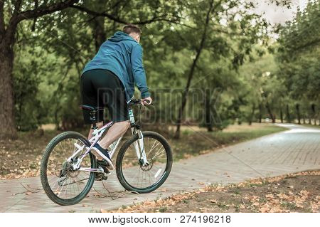 Young Caucasian Man Bicycles On Pink-and-white Bicycle Through The Abandoned Path In The Autumn Park