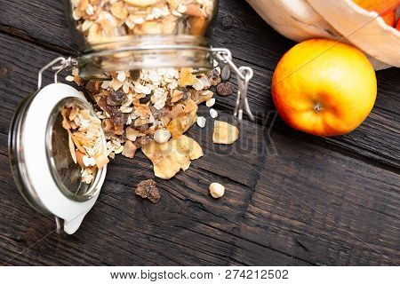 Homemade Granola In Glass Jar And Apples In Reusable Fabric Bag On Dark Wooden Table With Texture. H