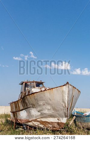 Abandoned Old Rusty Ship Staying On The Sea Coast Against Blue Sky In Byala, Bulgaria.