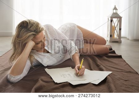 Beautiful Blonde Woman Lays On Floor, And Draw Design Skeches By Hand.