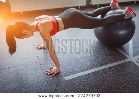 From Above Shot Of Slim Adult Woman In Sportswear Doing Lank Exercise On Swiss Ball While Working Ou