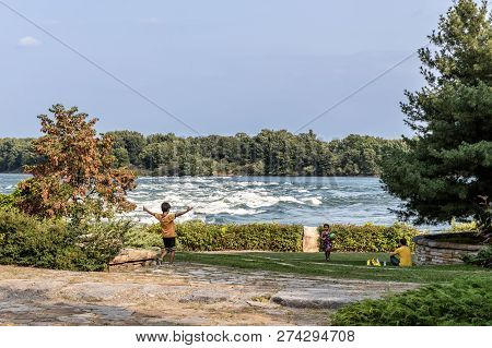 Lasalle, Quebec - August 15, 2018 - Horizontal Of Children Playing Ball In Front Of The Lachine Rapi